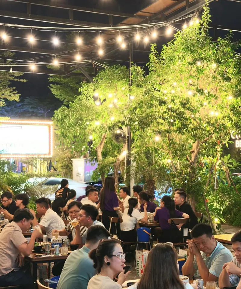 Sân vườn Cụng Beer buổi tối, khách ngồi kín bàn dưới đèn dây và cây xanh